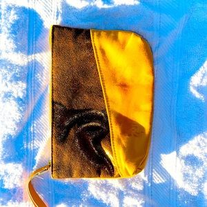 A mini makeup or accessories bag. Color yellow mustard. Has a brown glitter line